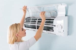 A Young Woman Cleaning Air Conditioning System At Home